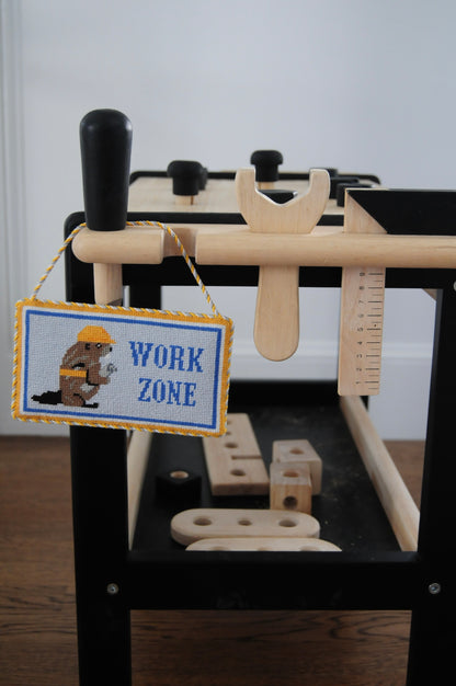 Toy workbench with tools and a 'Work Zone' needlepoint sign designed by Frances Mary.